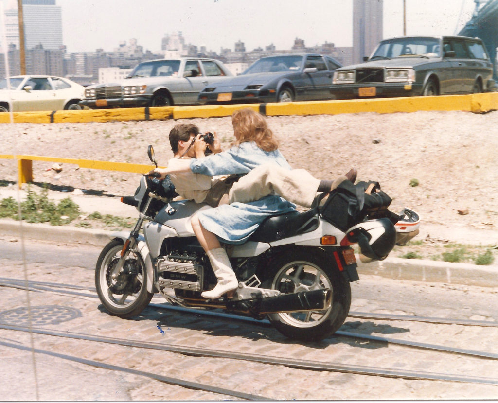 Lisa Rides motorcycle with train track and sand on cobble stone